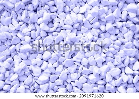 Texture of pure white pebbles tinted in pantone color 2022 very peri. Small stones on the ground.