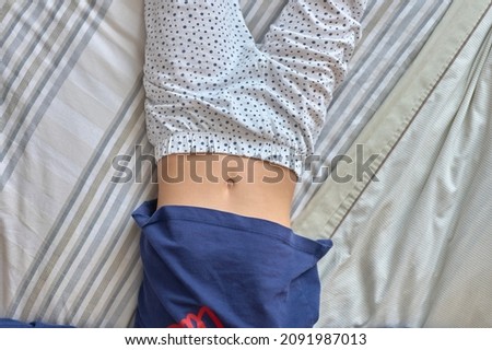 detail of a girl lying on a bed with her bellybutton exposed Royalty-Free Stock Photo #2091987013