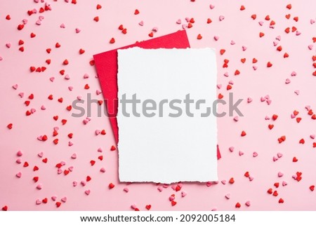 Happy Valentines Day composition. Blank paper card mockup and red envelope with small hearts confetti on pink background. Love, romance concept. Royalty-Free Stock Photo #2092005184