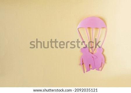 Abstract cardboard family of two elderly people and a rescue parachute. A minimalistic picture of the protection of elderly people in various situations