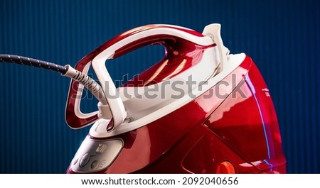 Red steam generator iron on a blue background