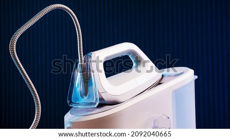 White steam generator iron on a blue background Royalty-Free Stock Photo #2092040665