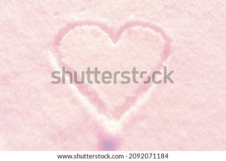 One hand drawn heart shape in the fresh snow.Top view,closeup,copy space.Calming coral tone color.
