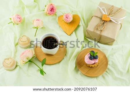 romantic breakfast for Valentine's Day. gift box, rosebuds, heart, cup of freshly made coffee. pastel background