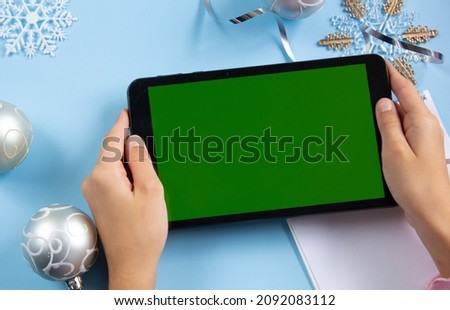 A tablet with a green screen against the background of New Year's paraphernalia. New Year's greetings. Background. Copyspase