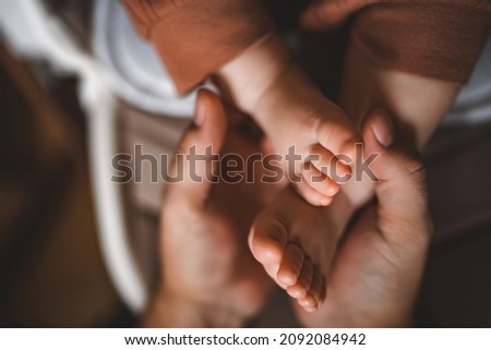 The father holds the baby's legs. Newborn in the hands of the Pope. Small children's feet, men's hands. Greeting card for father's day. Royalty-Free Stock Photo #2092084942
