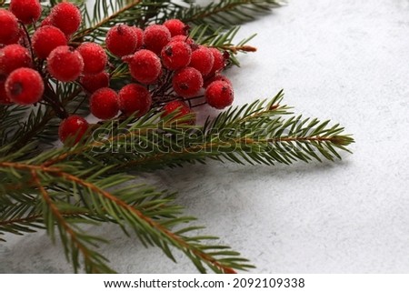 Christmas red berries decoration on the fir tree branches on gray surface. Christmas festive background