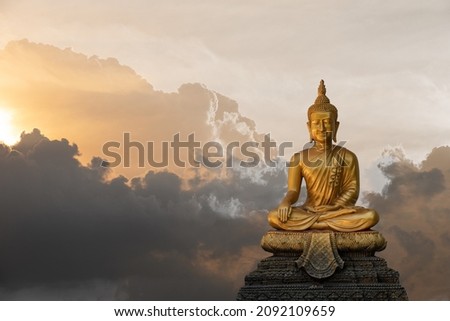 A peaceful superimposed and double exposure images of Golden Buddha statue from Wat Pathum Wanaram, Bangkok, Thailand and pink clouds. Buddha statue is posing “The attitude of subduing Mara".