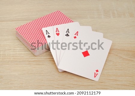 four aces are placed on top of a poker card pile on a wooden table