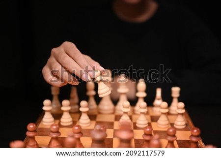 Businesswoman moving chess piece during chessboard competition. Business strategy concept.