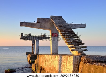 Sea barriers at dawn "Diving with boon is forbidden". Old coastal structures on the Black Sea beach in Sochi, Russia Royalty-Free Stock Photo #2092136230
