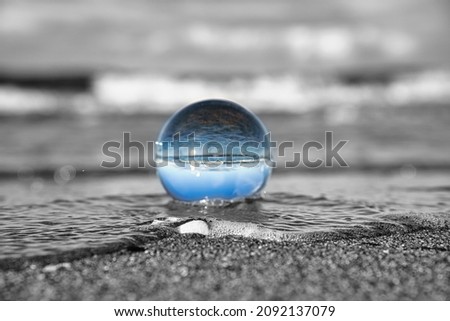 glass globe on the beach of the baltic sea. Black and white photo with a color glass ball