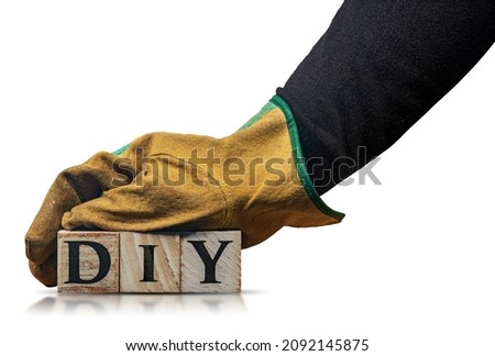 Manual worker with protective work gloves, holding the text DIY (Do It Yourself), made of wooden blocks, isolated on white background with reflections and copy space.