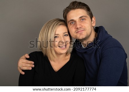 Portrait of a happy couple looking to the camera in front of grey background
