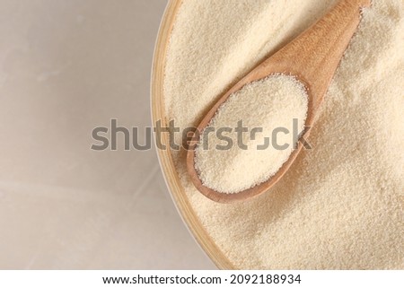 Bowl with semolina and spoon on light table, top view. Space for text Royalty-Free Stock Photo #2092188934