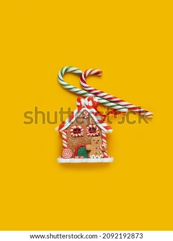 Gingerbread house, red clock, gift, lollipop, candy on a yellow background.