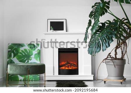 Stylish interior of living room with fireplace and tropical plant in pot