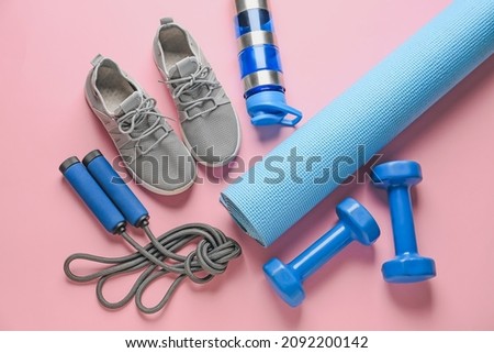 Sport shoes, yoga mat, bottle of water, dumbbells and skipping rope on color background Royalty-Free Stock Photo #2092200142