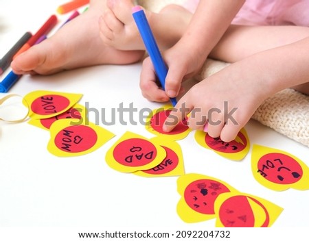Child sitting on the floor and making fun Valentine cards, funny crafts