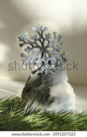 Minimal Christmas composition. Natural marble stand for presentation with  silver glitter snowflake and pine branches.