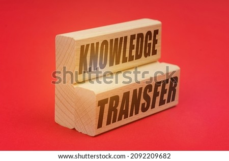 Business and economy concept. On a red background, wooden blocks with the inscription - KNOWLEDGE TRANSFER