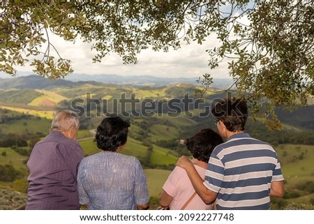 Group with two elderly couples talking animatedly and admiring a beautiful landscape on top of a mountain. the oldest over 80 years of age with completely white hair.