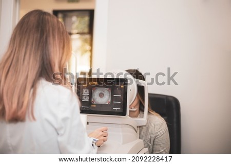 an optometrist uses a wide cone corneal topographer to take information from a patient's cornea. Royalty-Free Stock Photo #2092228417
