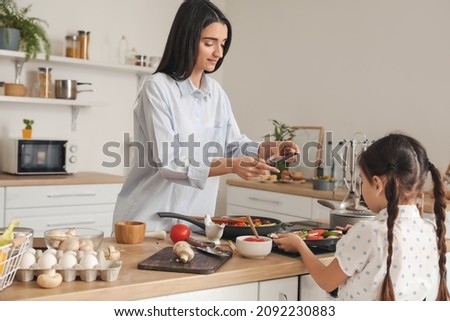Daughter and mother with mobile phone taking picture of tasty food in kitchen