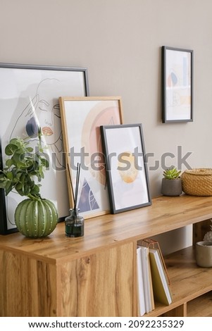 Book shelf with stylish pictures near light wall