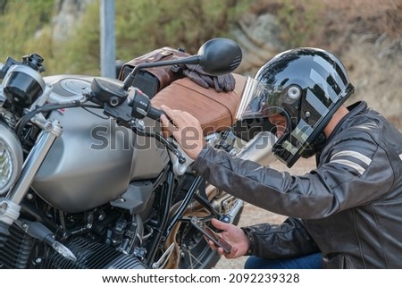 Biker calling with his mobile phone to the motorcycle insurance company Royalty-Free Stock Photo #2092239328