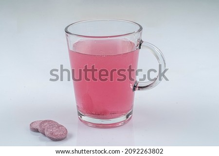 Effervescent tablet vitamin melting in glass cup.