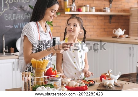 Daughter and mother with mobile phone taking picture of tasty pizza in kitchen