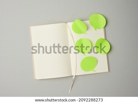blank paper green stickers in the shape of a cloud glued to white sheets of a notebook, gray background