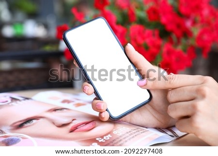 Woman holding mobile phone and pointing on blank screen, closeup