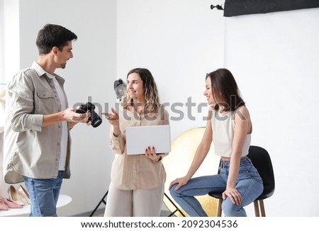 Stylist and photographer working with model in studio