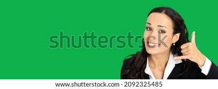 Businesswoman in black confident suit clothing showing call me hand sign gesture, over green colour background. Happy smiling gesturing brunette woman at studio. Business concept photo. Chroma key