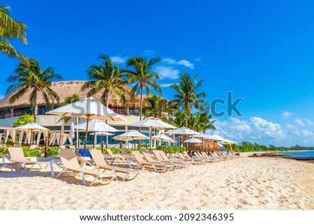 Palm trees parasols umbrellas and sun loungers at the reef coco beach resort on tropical mexican beach in Playa del Carmen Mexico. Royalty-Free Stock Photo #2092346395