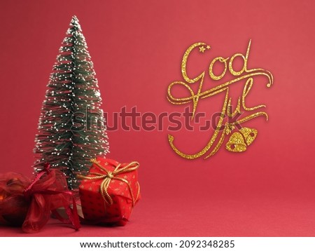 God Jul, Scandinavian Christmas greetings, Red Christmas gift box with golden bow and decoration on a red paper background with space for text or image