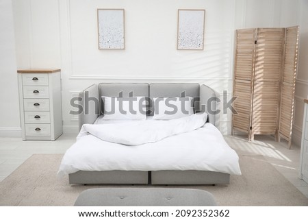 Stylish room interior with sleeper sofa near white wall. Additional place for guest Royalty-Free Stock Photo #2092352362