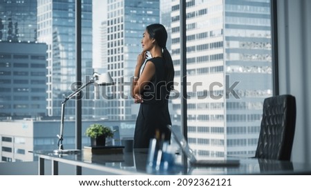 Successful Businesswoman in Stylish Dress Working on Laptop, Looking out of the Window at Big City. Confident Female CEO Analyze Financial Projects. Manager at Work Planning Marketing Campaign. Royalty-Free Stock Photo #2092362121
