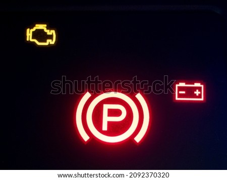 Red illuminated hand brake sign close-up.