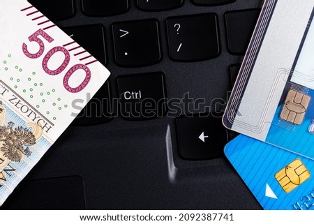 Polish 500 PLN banknote and credit cards arranged on the laptop keyboard. Cybersecurity of online shopping. Photo taken under artificial, soft light