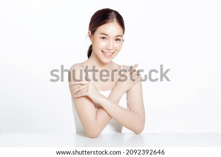 Asian woman with a beautiful face gathered in a brown ponytail and clean fresh smooth skin. Cute female model with natural makeup and sparkling eyes on white isolated background. Royalty-Free Stock Photo #2092392646