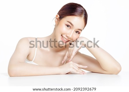 Asian woman with a beautiful face gathered in a brown ponytail and clean fresh smooth skin. Cute female model with natural makeup and sparkling eyes on white isolated background. Royalty-Free Stock Photo #2092392679