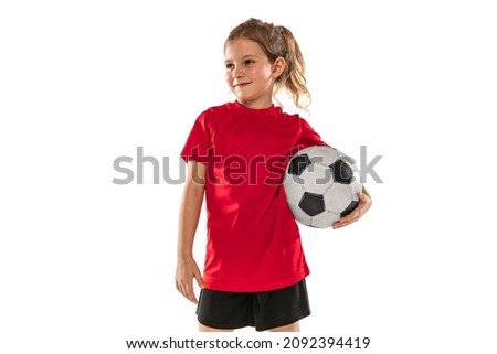 Girl, child, football player in red uniform holding ball and posing isolated over white background. Concept of action, sportive lifestyle, team game, health, energy, vitality. Copy space for ad