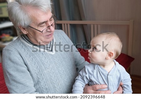 Family Relations of Elderly 60s Male and Baby Girl. Happy Old Man Holds a little Child on Hands. Gentle Hug and Love for Caucasian Grandchild in Slow Motion. Enjoy Family Time. s3niorlife
