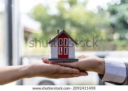 two people holding a miniature house model, photo of home insurance concept, when buying a new home should have home insurance to be sure if there is any danger to the home.