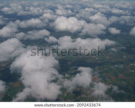Photography of blue sky with white clouds. Beautiful view through the aircraft window. Concepts of the beauty in nature, freedom and travel mood. Any European town is located at the land here