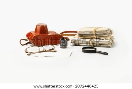 A stack of family photos and a film camera, glasses and a magnifier on a white background.