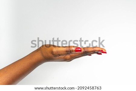 African American beautiful dark brown skin woman's hand open palm and arm isolated on white background with red nails. Closeup of hand of a young woman with long red manicure on nails.